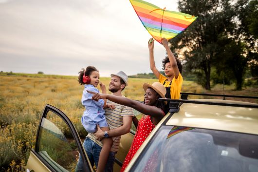 Family hanging out of a car with a kite