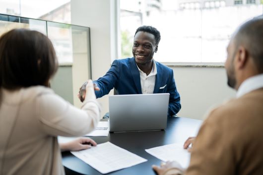 Man shaking hands with couple across desk