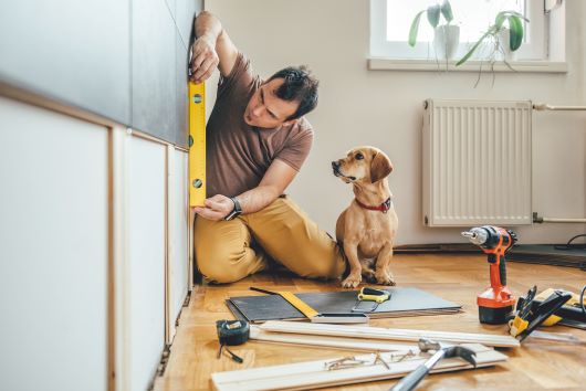 Man checking level while dog looks on